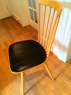 Chaise estampillée Baumann, en bois, galette en skai noir, dossier à barreaux, très confortable, dimensions : H 86, H assise 45, l 42 cm.