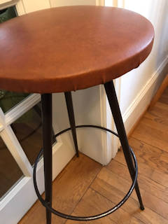 Élégant tabouret de bar, assise ronde au revêtement d’origine Skaï couleur cuir, piétement trépied en métal, dans son jus, dimensions : diamètre assise 33 cm, diamètre repose-pied 36 cm, H 75 cm.