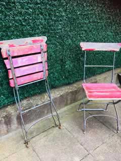 Paire de chaises anciennes de jardin, pliantes, structure métal, assise et dossier en lattes de bois, peinture rouge d’origine écaillée, dans leur jus.