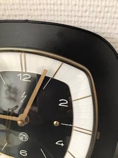 Horloge murale SMI, support formica carré, noir, aiguilles dorées, mécanisme quartz.