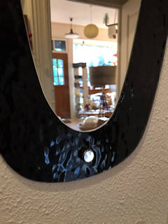 Miroir elliptique vintage, sur un support en verre teinté noir, idéal dans une entrée ou déco murale.