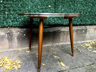 Authentique table basse tripode, de forme triangulaire, arrondie, pieds compas fuselés et embouts laiton, plateau Formica très coloré d’inspiration libre, champ doré avec liseré noir; Porte les traces du temps lui conférant tout son charme. Dimensions: H 50 cm, L 68 cm, l 62 cm.
