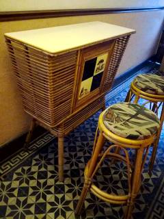 Bar vintage en rotin et ses deux tabourets hauts, plateau Formica, résistant et imperméable à tous vos cocktails, orné de 4 carreaux en céramique, pièce typique des années 60, bel état de conservation. Dimensions: H 111, L 101, P 42, H tabouret 76.