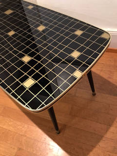 Bout de canapé ou table basse, plateau en verre sérigraphié avec motifs géométriques dorés sur fond noir, garni d’un champ doré avec liseré noir, sur 4 pieds compas en bois  et embouts laiton; dimensions : L 90 cm, l 45,5 cm, H 46 cm.