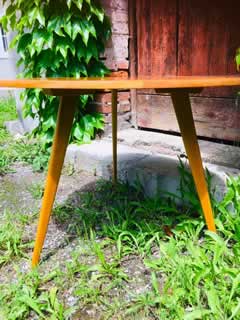 Table basse tripode, plateau triangulaire, en placage de bois blond, liseré marqueté, pieds compas, H 55, L 71cm.
